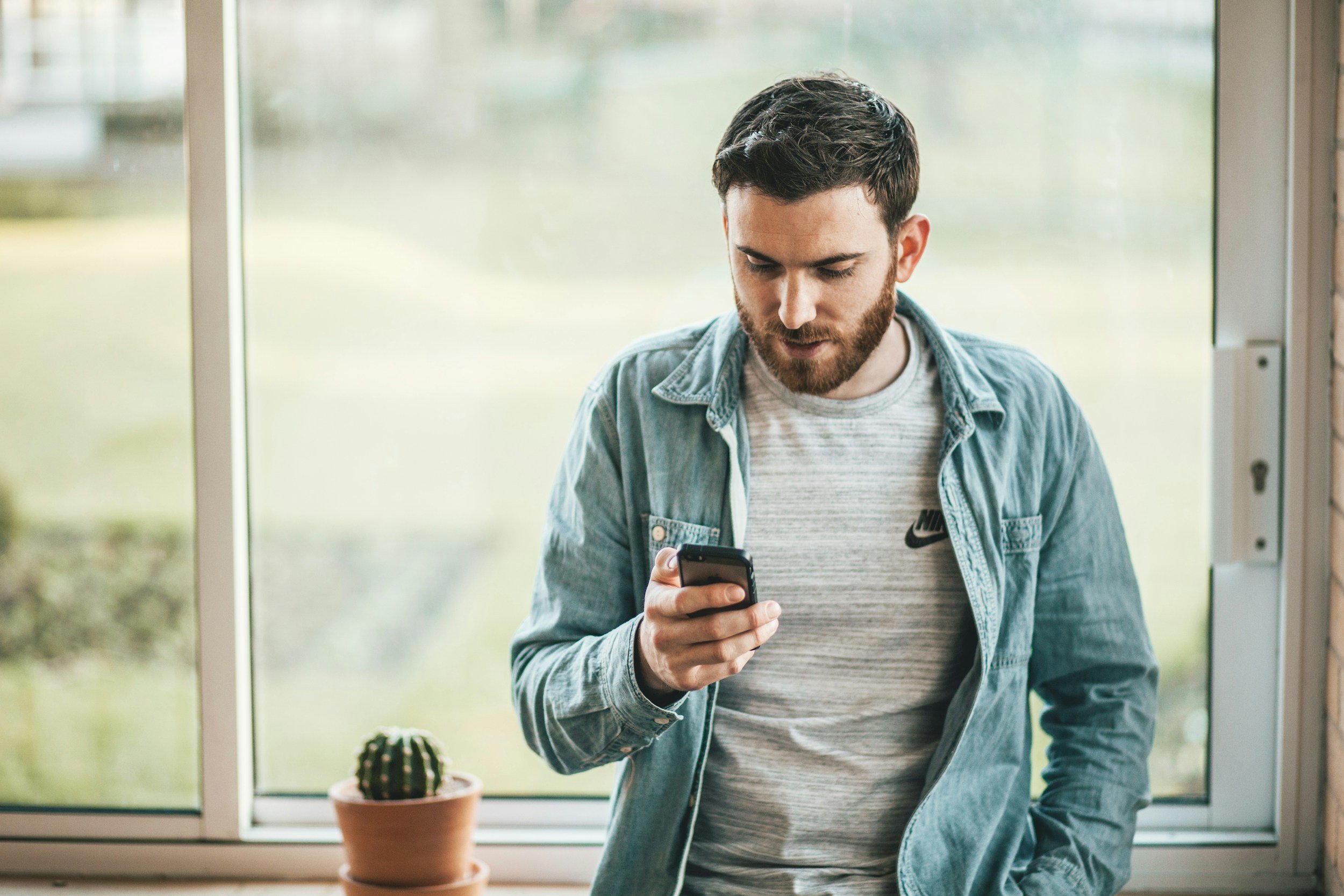 Man looking at phone near window